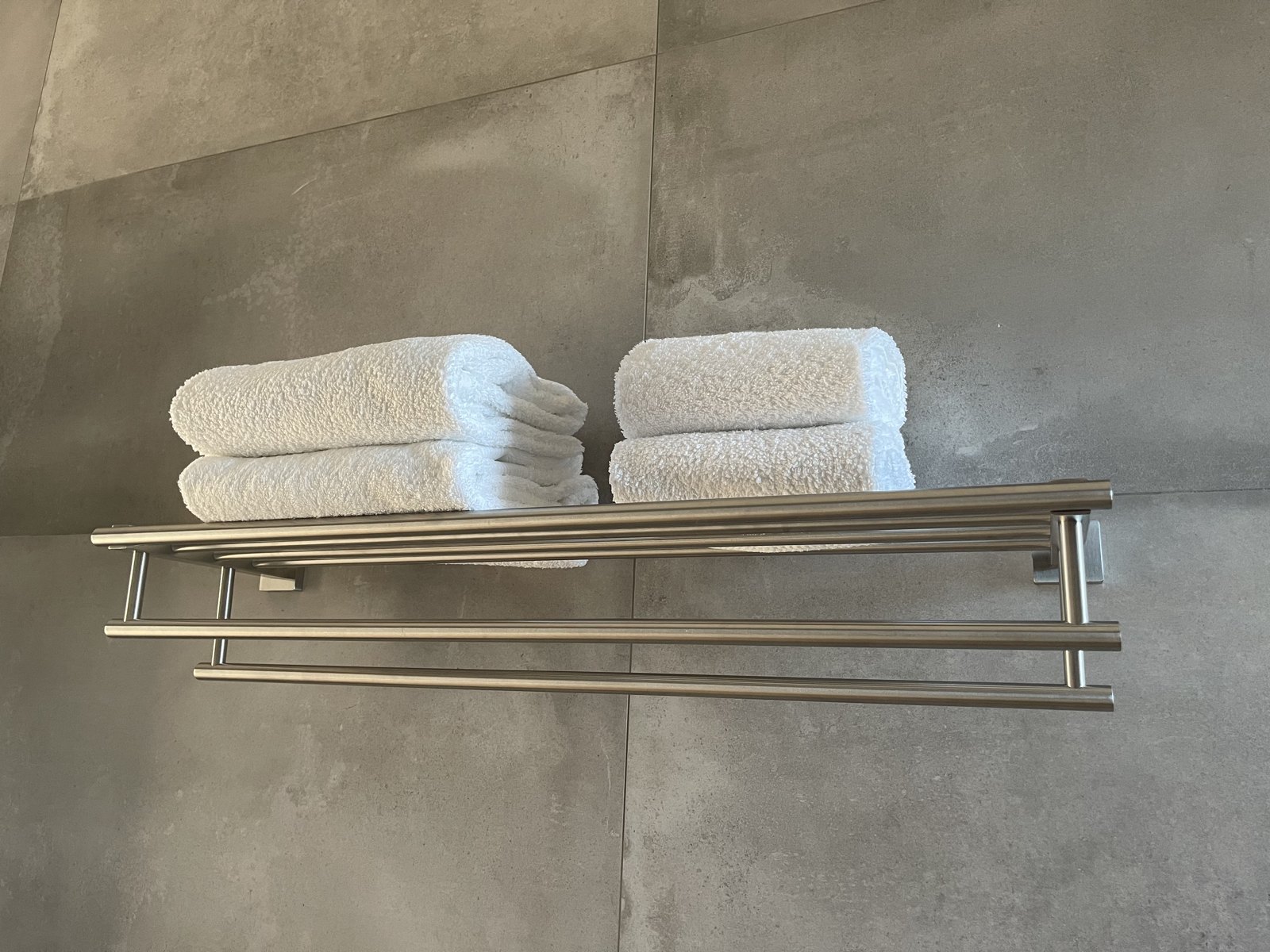 Heated towel rail with folded fresh white towels in the bathroom at Guesthouse Olival