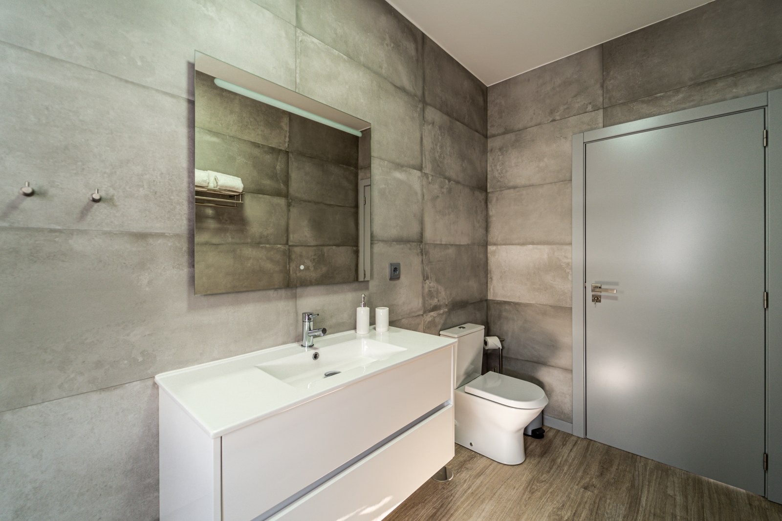 Bathroom vanity with white basin, large mirror and toilet at Guesthouse Olival, Madeira