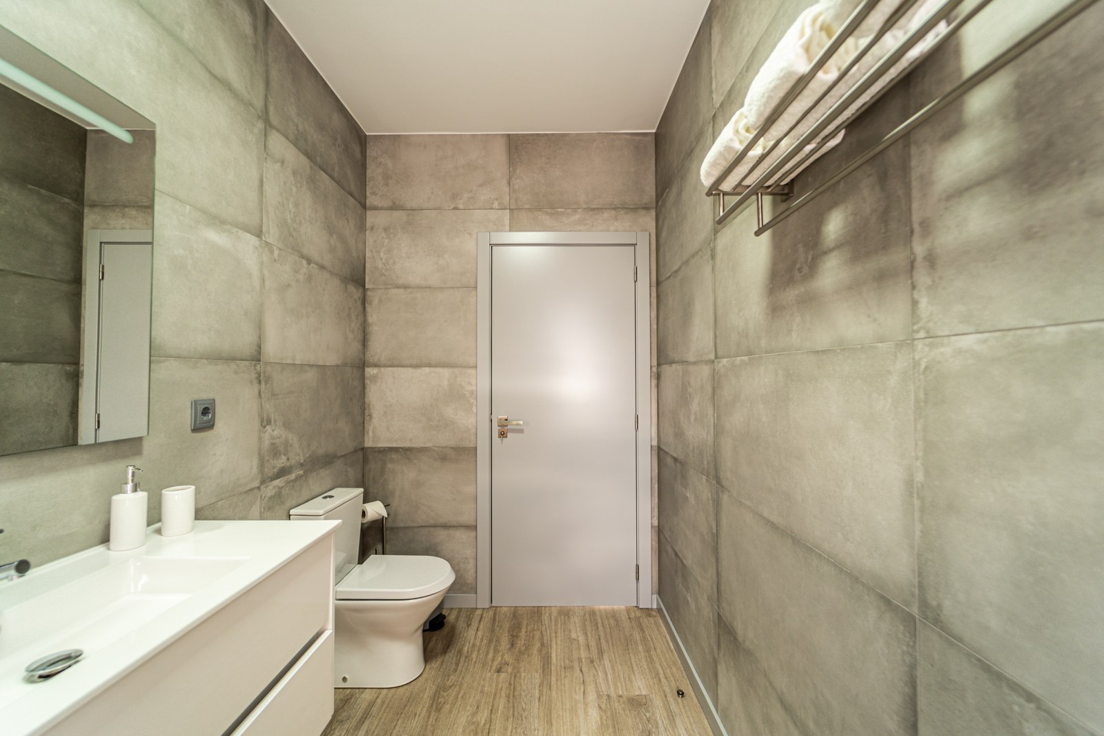 Bathroom with toilet, vanity and towel rail in grey tiling at Guesthouse Olival, Madeira