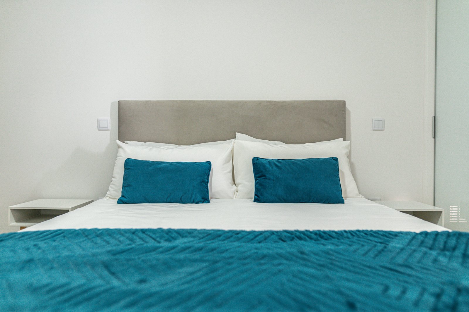 Close-up of the king bed with upholstered headboard and teal pillows at Guesthouse Olival