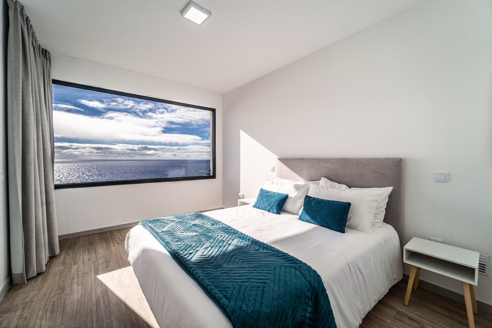 Bedroom with king bed and a wide ocean-view window at Guesthouse Olival, Gaula, Madeira