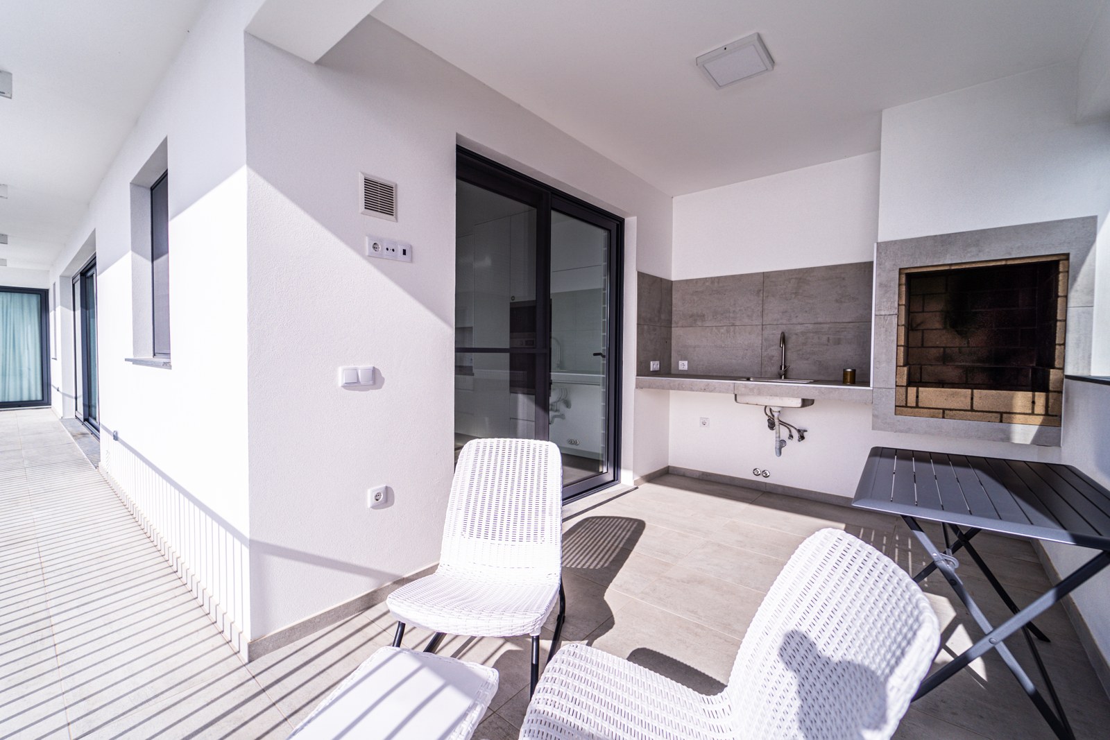 Covered terrace with seating, barbecue and sliding doors to the interior at Guesthouse Olival