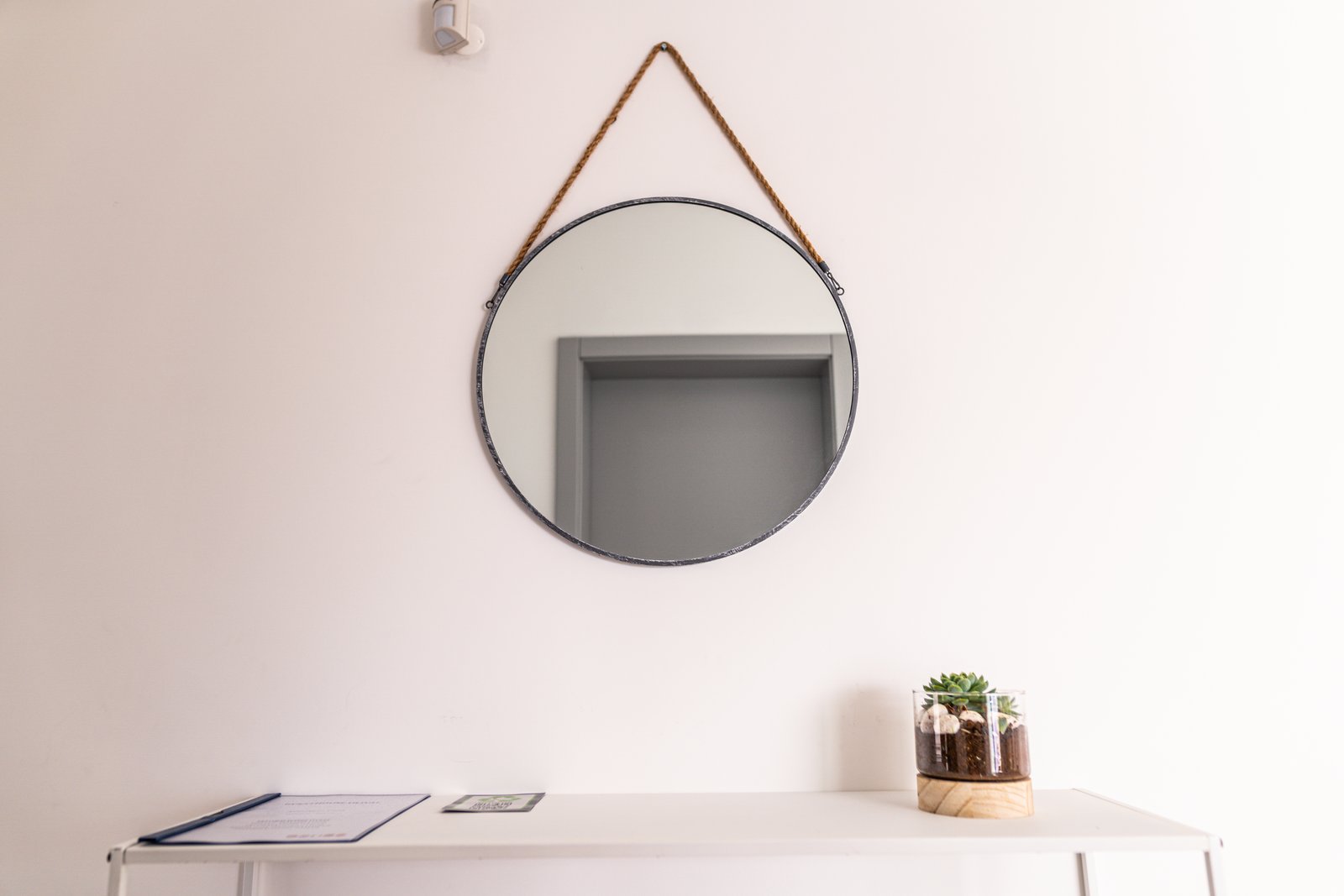 Entryway with a round mirror, console table and guest welcome book at Guesthouse Olival, Madeira