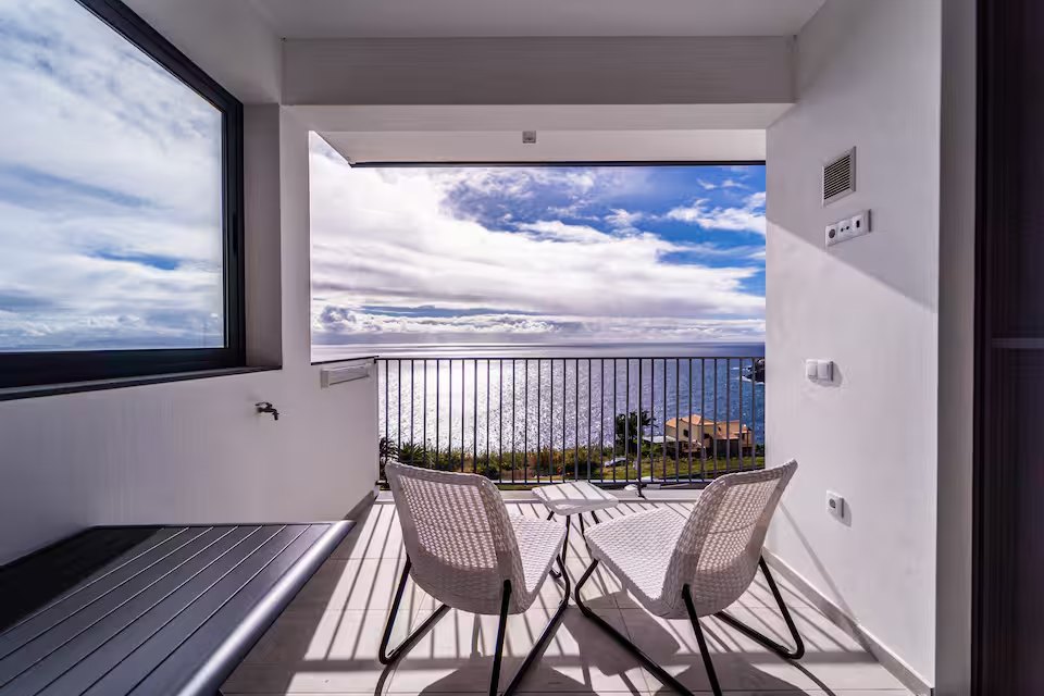 Covered terrace dining nook framing a sweeping ocean view at Guesthouse Olival, Madeira